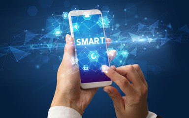 Female hand holding smartphone with SMART inscription, modern technology concept