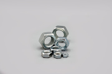 Metal nuts isolated on gray background. New and shiny chrome nuts. Copy space.