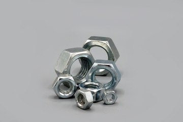 Metal nuts isolated on gray background. New and shiny chrome nuts. Copy space.