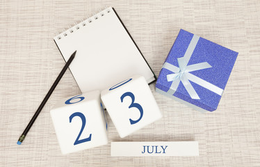 Calendar with trendy blue text and numbers for July 23 and a gift in a box.