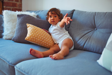 Beautiful toddler child girl wearing white t-shirt sitting on the sofa