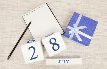 Calendar with trendy blue text and numbers for July 28 and a gift in a box.