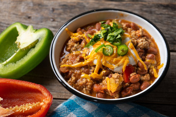 Texmex dish called "Chili con carne" with cheese and sour cream on wooden background - Powered by Adobe
