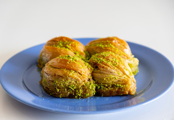 Turkish Midye Baklava ( Mussel Shaped Baklava ) with Green Pistachio Powder and Butter Cream. Turkish   baklava on blue dish
