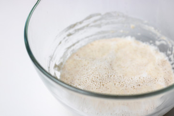 raw sour dough whole wheat pastry for bread, prosess of mixing pre-dough in glass bowl, knead, horizontal with copy space, selectuve focus, healthy food, nutritious. White background