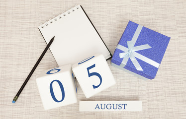 Calendar with trendy blue text and numbers for August 5 and a gift in a box.