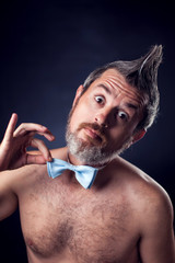 A portrait of naked man with iroquois wearing  butterfly tie in front of black background