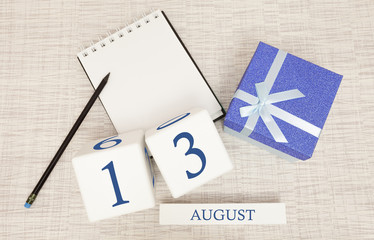 Calendar with trendy blue text and numbers for August 13 and a gift in a box.
