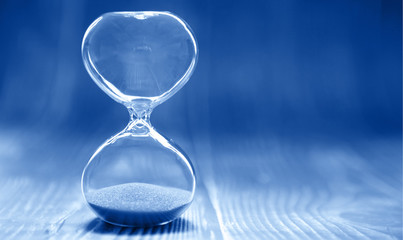 Hourglass on a modern trendy blue background, time and glass