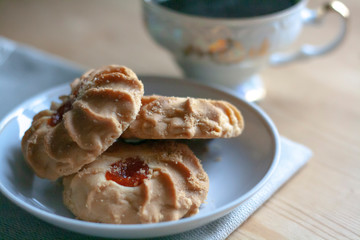 A cup of coffee and cookies in a saucer on a napkin on a wooden table