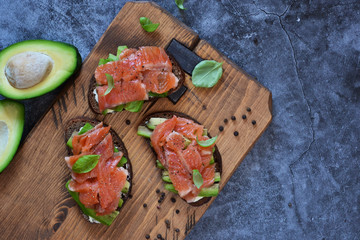 Sandwich with avocado and salmon on a concrete background. View from above.