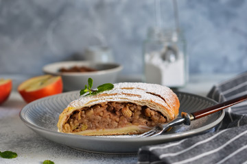 Strudel with apples, nuts and raisins on a concrete background.