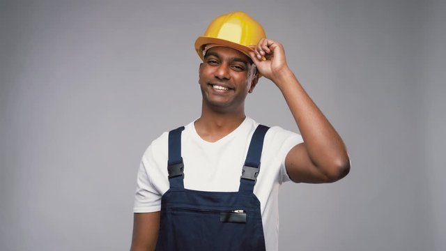 profession, construction and building - happy smiling indian worker or builder in helmet over grey background