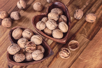 walnuts in wooden bowls in the form of hearts top view. background with walnuts in wooden bowls and on the table.