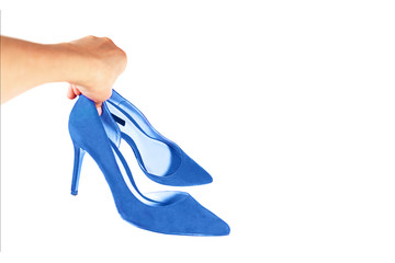 Woman holds fashionable blue shoes in her hand, isolated.