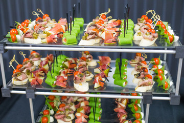 Different canapes with smoked salmon, cucumber, tomatoes, cheese, meat. Breakfast buffet table with a variety of snacks. Buffet served table with snacks,fruits, canape, sweets and appetizers