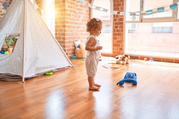 Beautiful caucasian infant playing with toys at colorful playroom. Happy and playful at kindergarten.