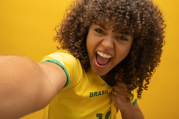 Fototapeta Brazil supporter. Brazilian woman fan celebrating on soccer / football match on yellow background. Brazil colors. obraz