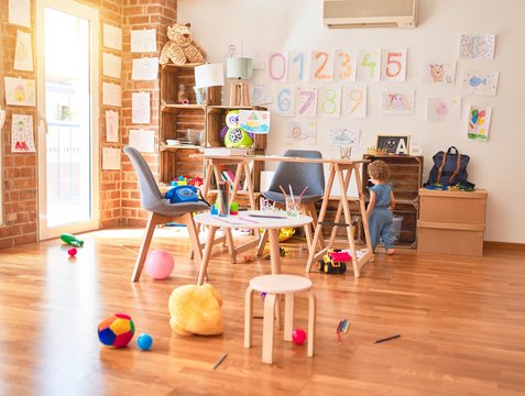 Beautiful caucasian infant playing with toys at colorful playroom. Happy and playful at kindergarten.