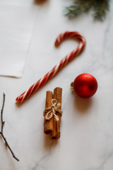 Christmas background. Christmas decorations, holiday decorations, fir branches, red balls, cinnamon and red Lollipop cane on a light stone background top view. 