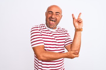 Middle age handsome man wearing striped t-shirt standing over isolated white background smiling with happy face winking at the camera doing victory sign. Number two.