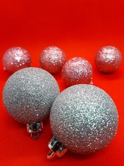  close-up of festive multi-colored ornaments for a Christmas tree, balls and gifts on a bright abstract red background