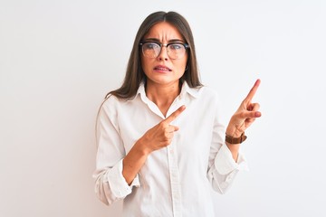 Young beautiful businesswoman wearing glasses standing over isolated white background Pointing aside worried and nervous with both hands, concerned and surprised expression