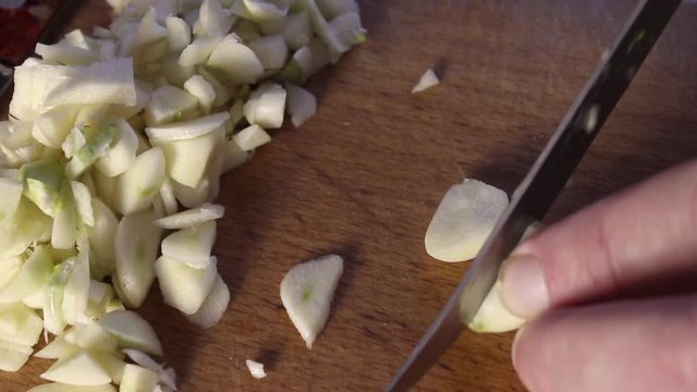 men's hands cut with a knife finely cloves of garlic on a wooden cutting Board