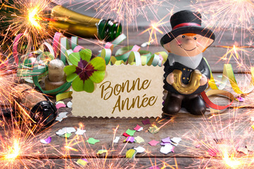 Chalkboard with four leaf clover and chimney sweeper and sparklers with bonne annee 2020 on wooden...