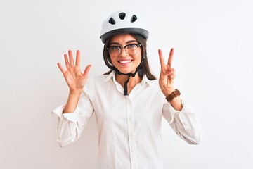 Beautiful businesswoman wearing glasses and bike helmet over isolated white background showing and pointing up with fingers number seven while smiling confident and happy.