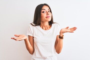 Young beautiful woman wearing casual t-shirt standing over isolated white background clueless and...