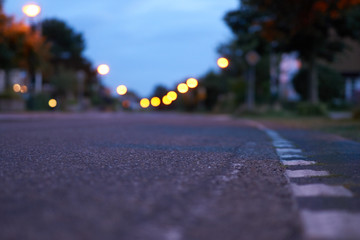 Straße in Dämmerung mit Lichtern und Fahrstreifen