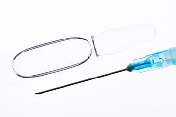 vaccine ampoule and disposable injection needle on a white background.