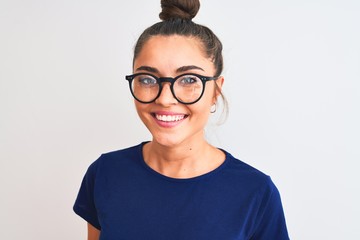Beautiful woman with bun wearing blue t-shirt and glasses over isolated white background with a...