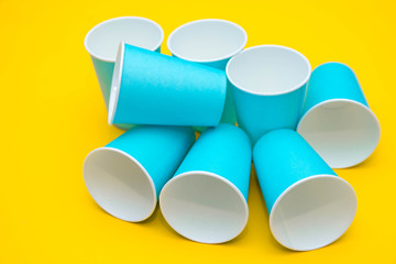 Many blue paper disposable cups on yellow background. Set for party. Top view. Minimalist Style. Copy, empty space for text