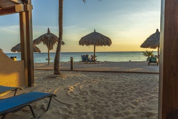 Gorgeous view on sandy beach and Atlantic Ocean from a room. Sun beds and umbrellas on turquoise water and blue sky background. Aruba island. 