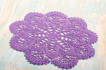 Vintage crochet round purple cotton lace doily with delicate ornament on light wood background....