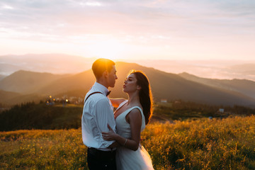 A man and a woman in a white dress in the sun, mountains and hills in the background