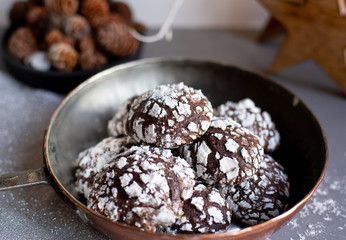 Home baked chocolate crinkle cookies in icing sugar.  Cracked chocolate biscuits in a copper pan on Christmas background. Chocolate Christmas brown cookies in powdered sugar with cracks. Copy space.