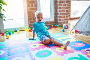 Young caucasian kid playing at kindergarten with toys. Preschooler boy happy at playroom.