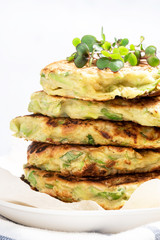 Vegetarian zucchini pancakes served with microgreens. Zucchini fritters close-up, front view. Delicious vegetarian food. Vegetable pancakes.