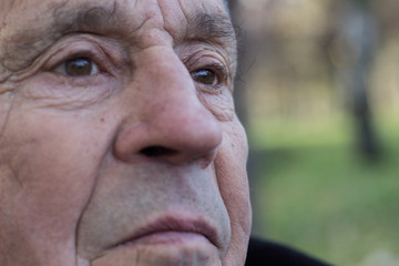 Eyes of a senior man, outdoors, nature. Looking away, thoughtful, thinking. Close up of senior man face and eye