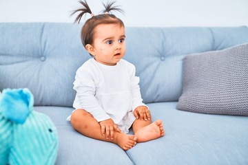 Beautiful infant happy at kindergarten around colorful toys on the sofa