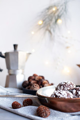 Home baked chocolate crinkle cookies in icing sugar.  Cracked chocolate biscuits in a white plate on Christmas background. Chocolate Christmas brown cookies in powdered sugar with cracks. Copy space.