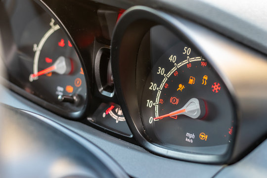 Dynamic angle of a vehicle instrument panel/binnacle, showing a blurred rev counter, speedometer and warning lights.