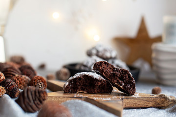 Home baked chocolate crinkle cookies in icing sugar.  Cracked chocolate biscuits in a white plate on Christmas background. Chocolate Christmas brown cookies in powdered sugar with cracks. Copy space.