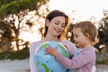 Portrait of happy mother looking together with her little daughter at Earth beach ball