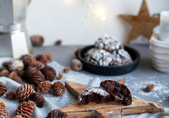 Home baked chocolate crinkle cookies in icing sugar.  Cracked chocolate biscuits in a white plate on Christmas background. Chocolate Christmas brown cookies in powdered sugar with cracks. Copy space.