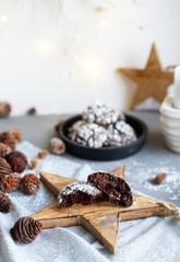 Home baked chocolate crinkle cookies in icing sugar.  Cracked chocolate biscuits in a white plate on Christmas background. Chocolate Christmas brown cookies in powdered sugar with cracks. Copy space.