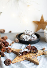 Home baked chocolate crinkle cookies in icing sugar.  Cracked chocolate biscuits in a white plate on Christmas background. Chocolate Christmas brown cookies in powdered sugar with cracks. Copy space.